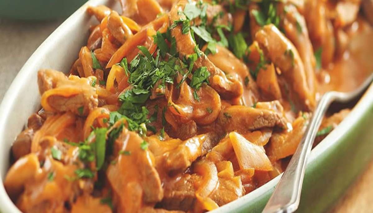 Close-up of creamy beef stroganoff with mushrooms and fresh herbs in a serving dish, ready to serve