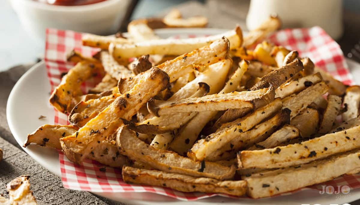Low-carb jicama fries baked to perfection with savory seasoning Golden roasted jicama fries seasoned with herbs served in a casual basket setup
