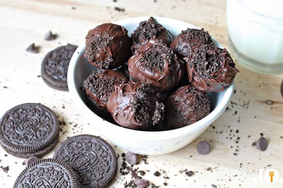 Rich and creamy Oreo truffle bites perfect for dessert or snacking Chocolate Oreo balls with cookie crumbs served in a bowl alongside sandwich cookies and a glass of milk