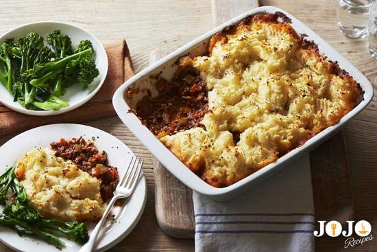 Top view of creamy mashed potato-topped Shepherd’s Pie served with greens.