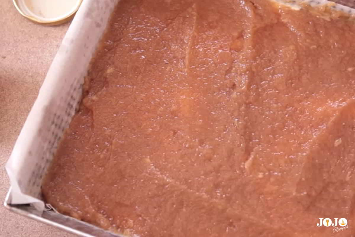 Step 3: Pour the batter into a greased and floured pan Pouring applesauce cake batter into a greased square baking pan