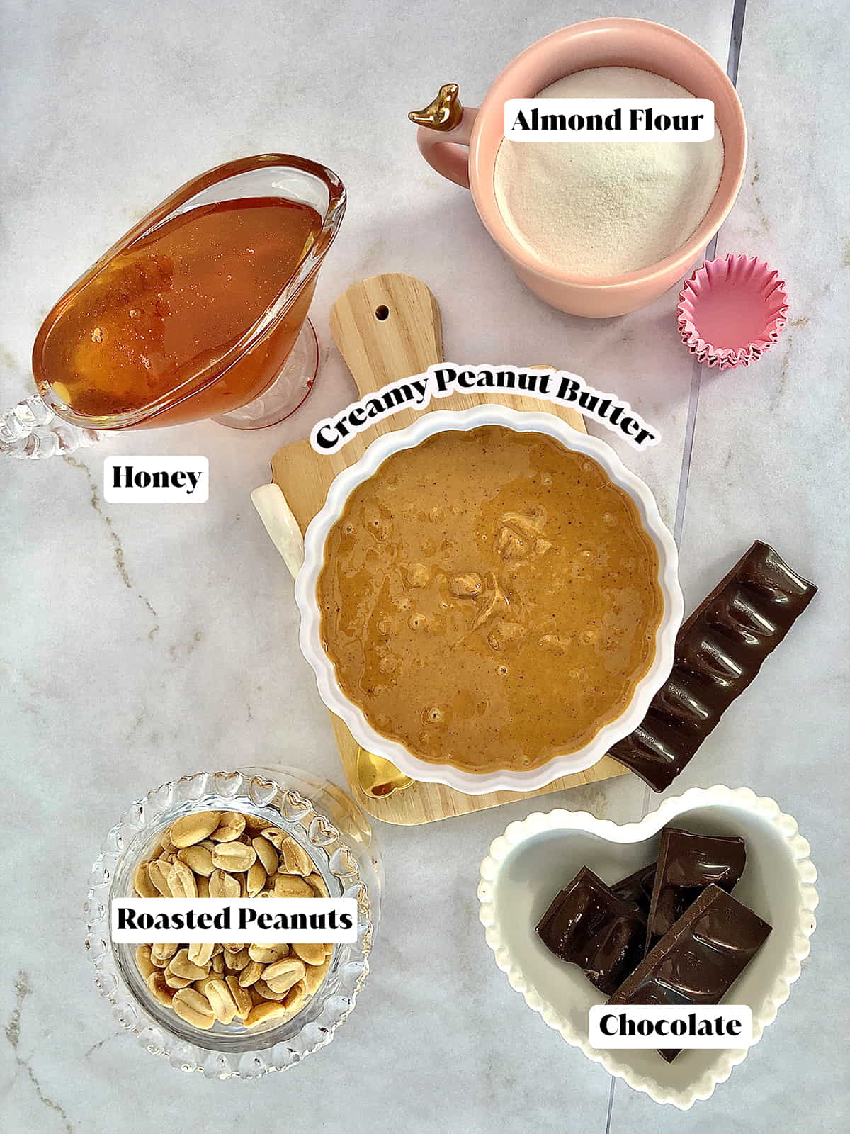 Ingredients for a peanut butter balls recipe including creamy peanut butter, honey, almond flour, roasted peanuts, and semi-sweet chocolate
