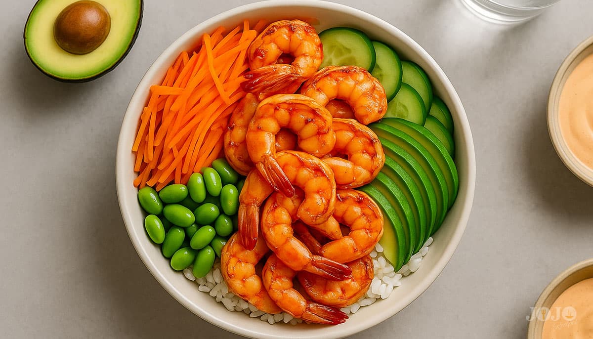 Asian shrimp bowl recipe with jasmine rice, shrimp, shredded carrots, edamame, cucumbers, avocado, and sriracha mayo