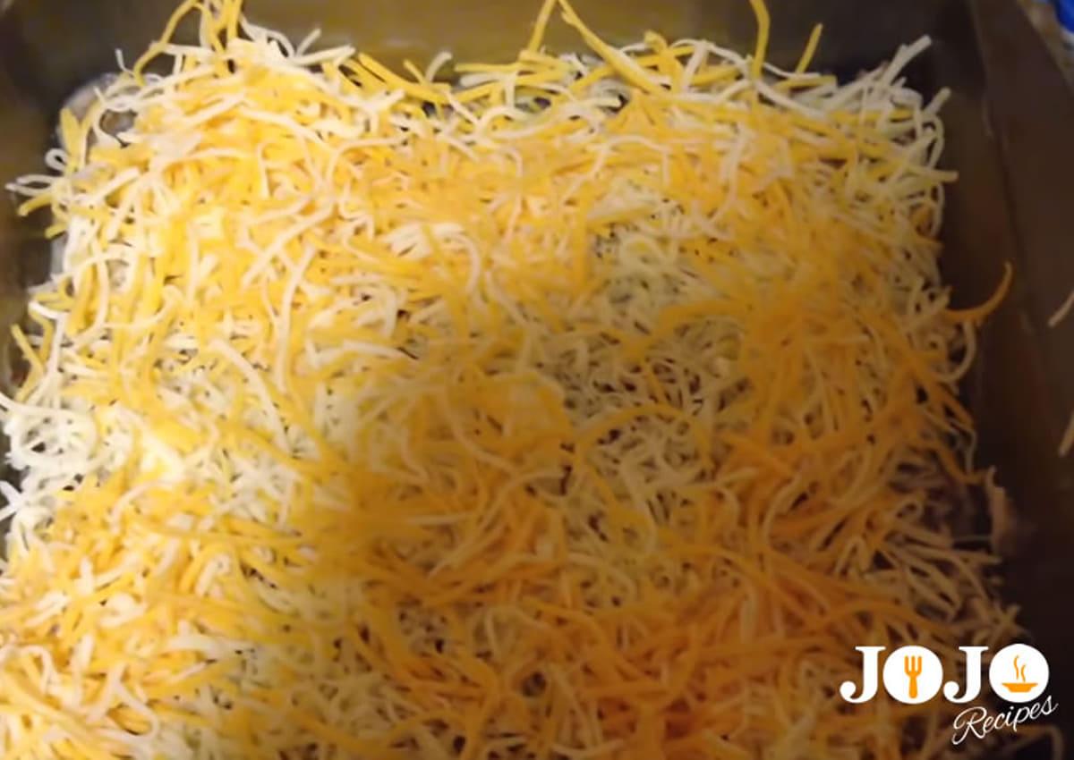 Shredded cheddar cheese layered over ground beef filling for Tater Tot Casserole recipe
